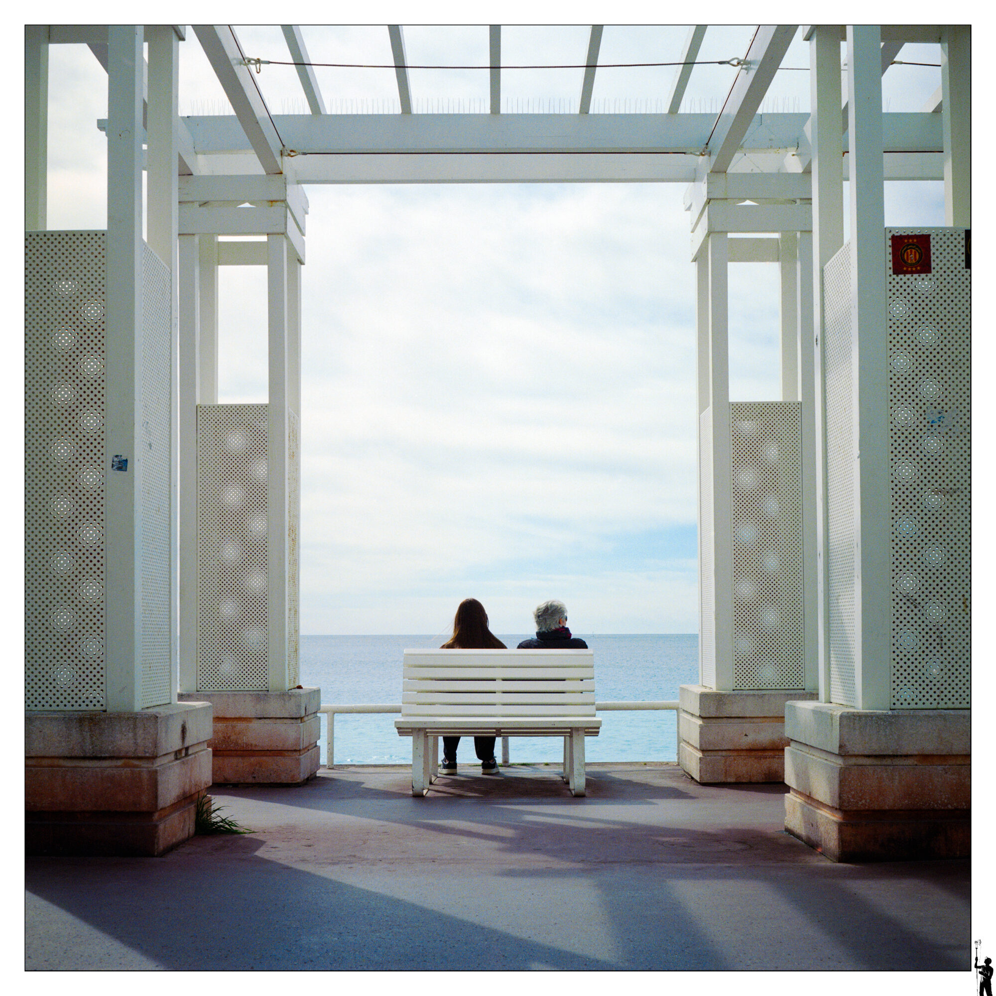 Sur la célèbre et belle promenade des Anglais à Nice. Le soir, la lumière est magnifique et crée de belles ombres. Ici les beaux bancs blancs attirent toujours du monde. Même fin Mars.